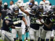 Seattle Seahawks cornerback Ryan Neal (35) is celebrated by his teammates after intercepting a pass, during the first half of an NFL football game against the Miami Dolphins, Sunday, Oct. 4, 2020 in Miami Gardens, Fla.