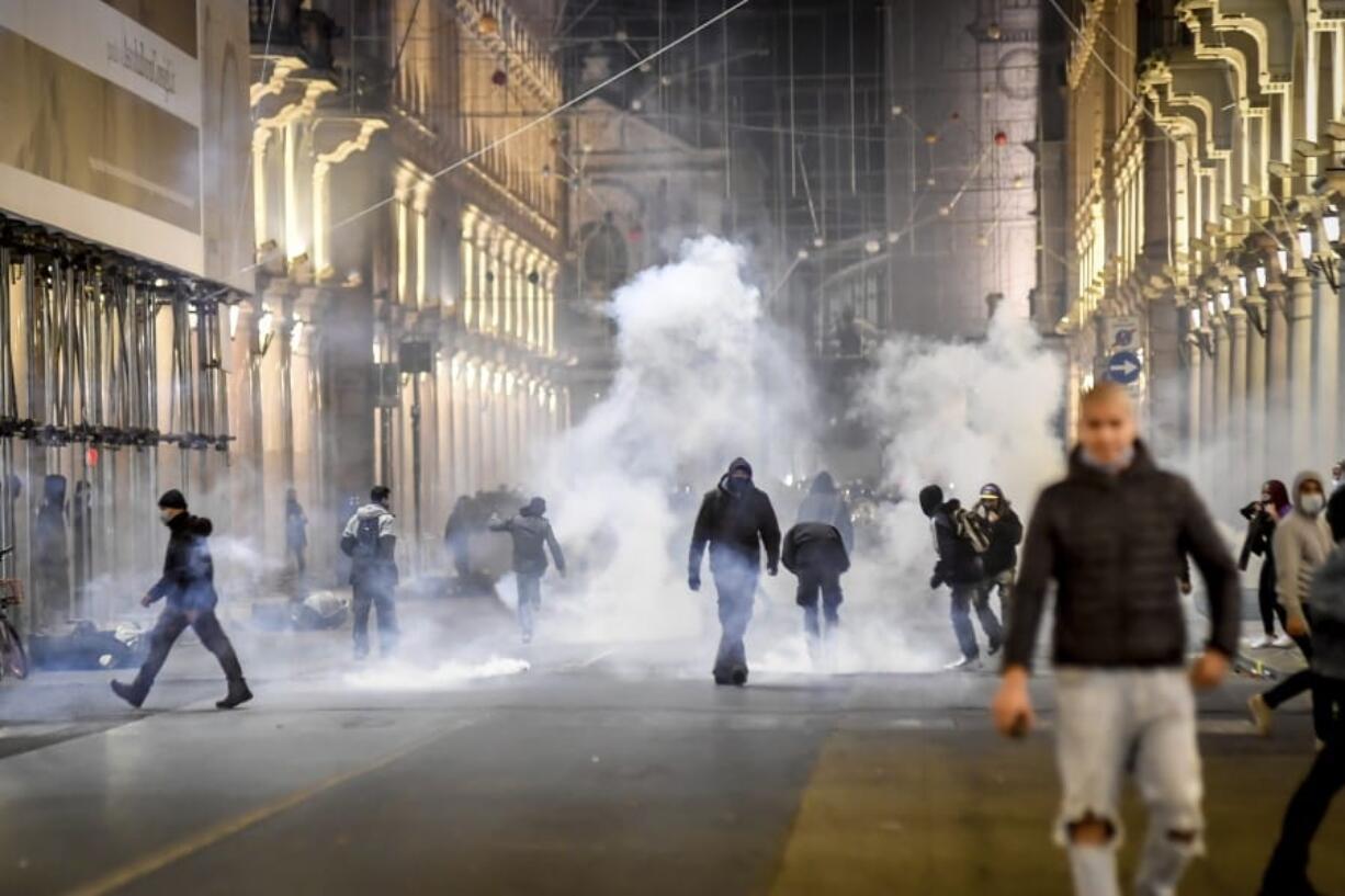 Smoke billows as clashes broke out during a protest against the government restriction measures to curb the spread of COVID-19 in Turin, Italy, Monday, Oct. 26, 2020. Protesters turned out by the hundreds in Italian several cities and towns on Monday to vent anger, sometimes violently, over the latest anti-COVID-19 rules, which force restaurants and cafes to close early, shutter cinema, gyms and other leisure venues. In the northern city of Turin, demonstrators broke off from a peaceful protest and hurled smoke bombs and bottles at police in the city square where the Piedmont regional government is headquartered.