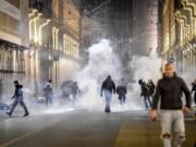 Smoke billows as clashes broke out during a protest against the government restriction measures to curb the spread of COVID-19 in Turin, Italy, Monday, Oct. 26, 2020. Protesters turned out by the hundreds in Italian several cities and towns on Monday to vent anger, sometimes violently, over the latest anti-COVID-19 rules, which force restaurants and cafes to close early, shutter cinema, gyms and other leisure venues. In the northern city of Turin, demonstrators broke off from a peaceful protest and hurled smoke bombs and bottles at police in the city square where the Piedmont regional government is headquartered.