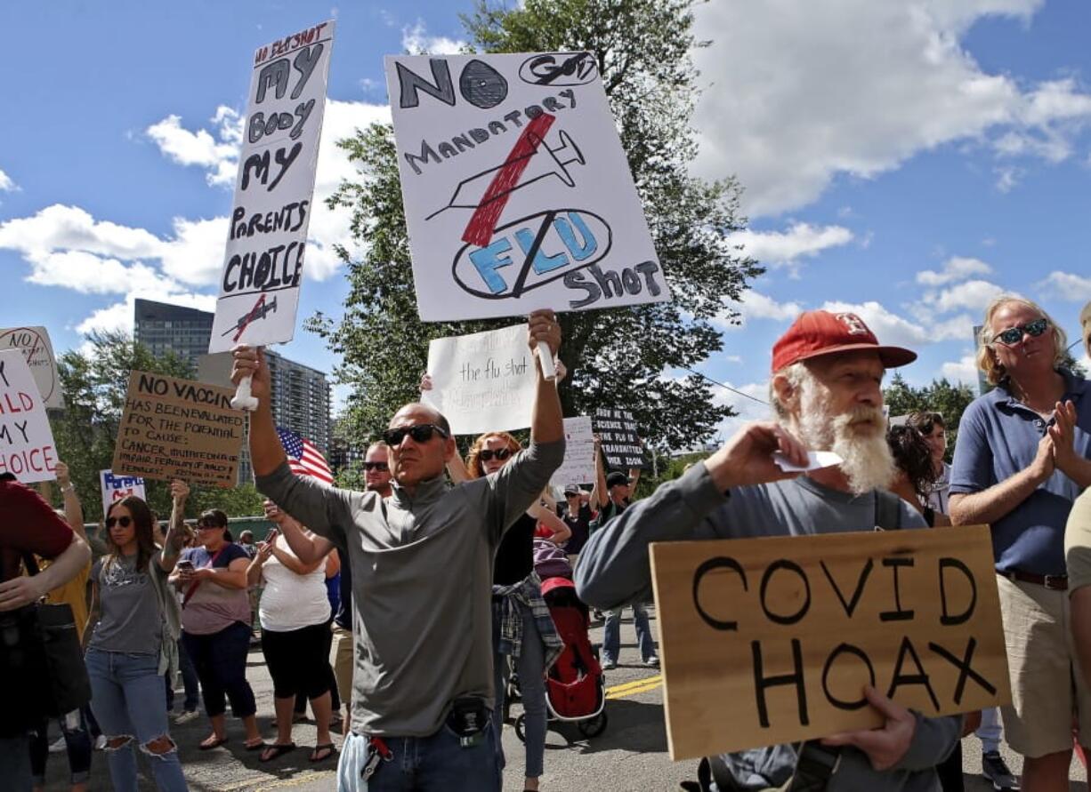 FILE - In this Aug. 30, 2020 file photo, Sal Lando, left, of Sterling, holds up signs during a protest against mandatory flu vaccinations, outside the Massachusetts State House, in Boston. Years before this year&#039;s anti-mask and reopening demonstrations, vaccine opponents were working on reinventing their image around a rallying cry of civil liberties and medical freedom. Now, boosted by the pandemic and the political climate, their rebranding is appealing to a different subset of society invested in civil liberties -- and, some health officials say, undercutting public health efforts during a critical moment for vaccines.