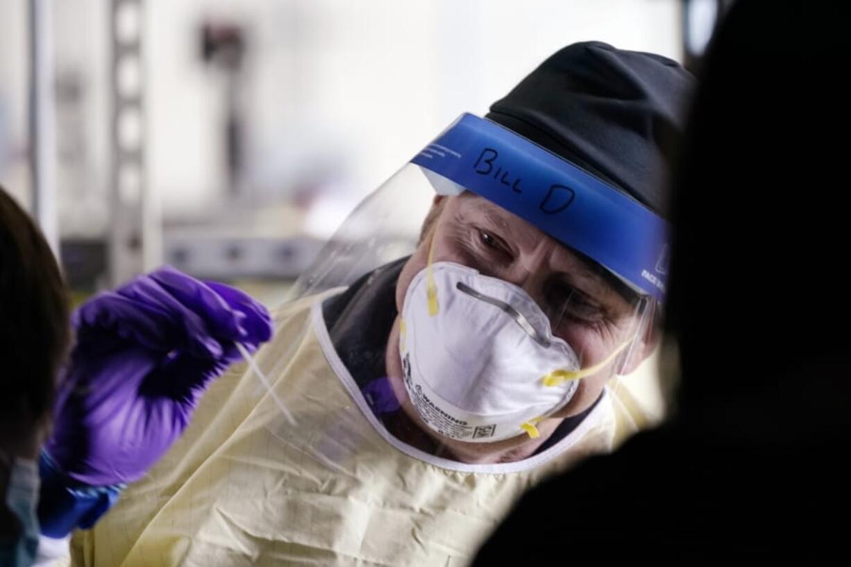 Seattle firefighter Bill Dennis reaches in to take a sample from a passenger in a car at a free COVID testing site Friday, Oct. 23, 2020, in Seattle. The United States is approaching a record for the number of new daily coronavirus cases in the latest ominous sign about the disease&#039;s grip on the nation, as states from Connecticut to Idaho reel under the surge.