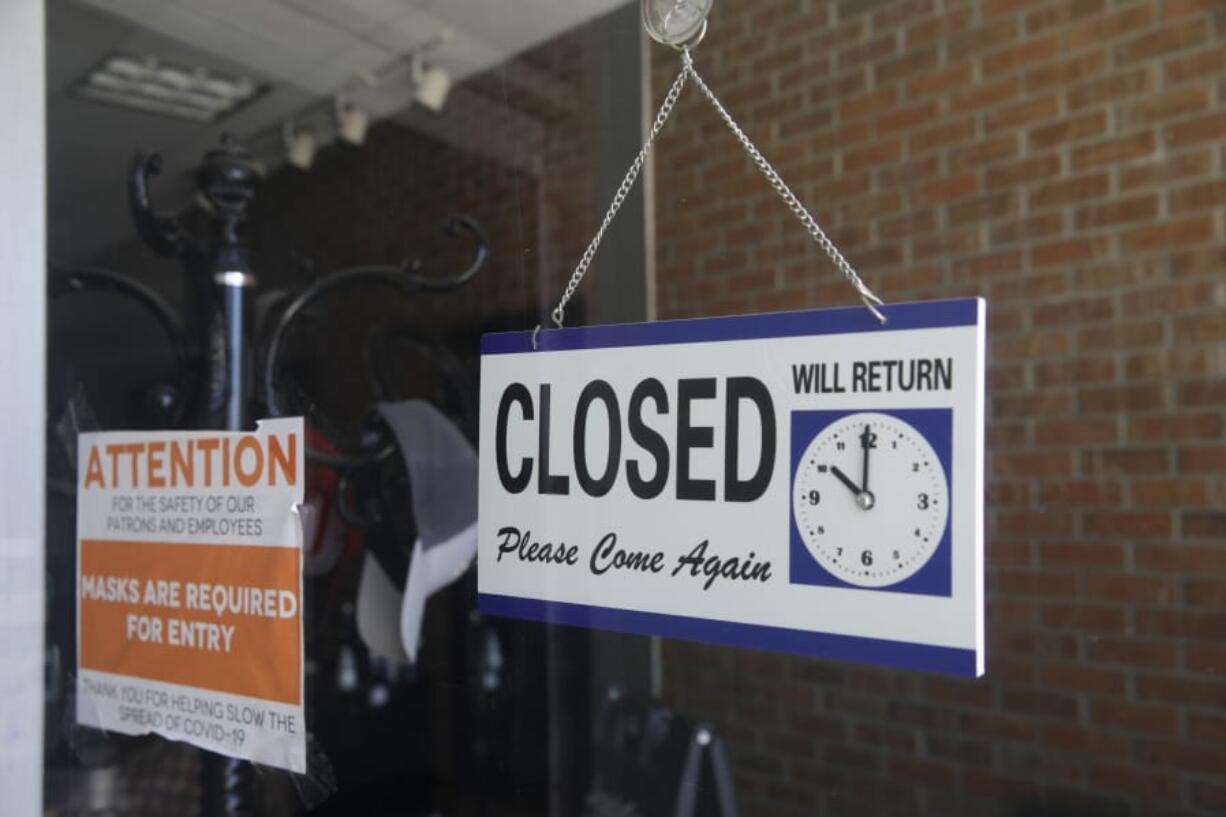 FILE - In this July 18, 2020 file photo a closed sign hangs in the window of a barber shop in Burbank, Calif.  A critical snapshot of the job market and the economy to be released Friday, Oct. 2,  is expected to show a further deceleration in hiring as the nation&#039;s viral caseload creeps higher just as financial aid from the government has faded.