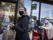 Pedestrians in protective masks pass a storefront on Thursday, Oct. 15, 2020, as restrictions on operations are imposed due to an increase in COVID-19 infections in the Far Rockaway neighborhood of the borough of Queens in New York. After shutdowns swept entire nations during the first surge of the coronavirus earlier this year, some countries and U.S. states are trying more targeted measures as cases rise again around the world. New York&#039;s new round of shutdowns zeroes in on individual neighborhoods, closing schools and businesses in hot spots measuring just a few square miles.