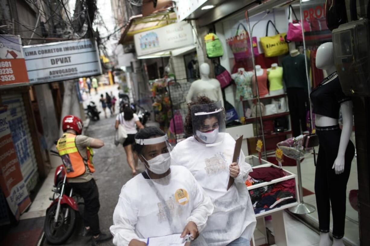 Health workers walk through the Rocinha slum to test people for COVID-19 as part of a rapid test campaign by the civilian organization &quot;Bora Testar,&quot; or &quot;Let&#039;s Test&quot; in Rio de Janeiro, Brazil, Thursday, Oct. 8, 2020. Financed by crowdfunding and donations, the organization says it aims to test up to 300 people in the slum.