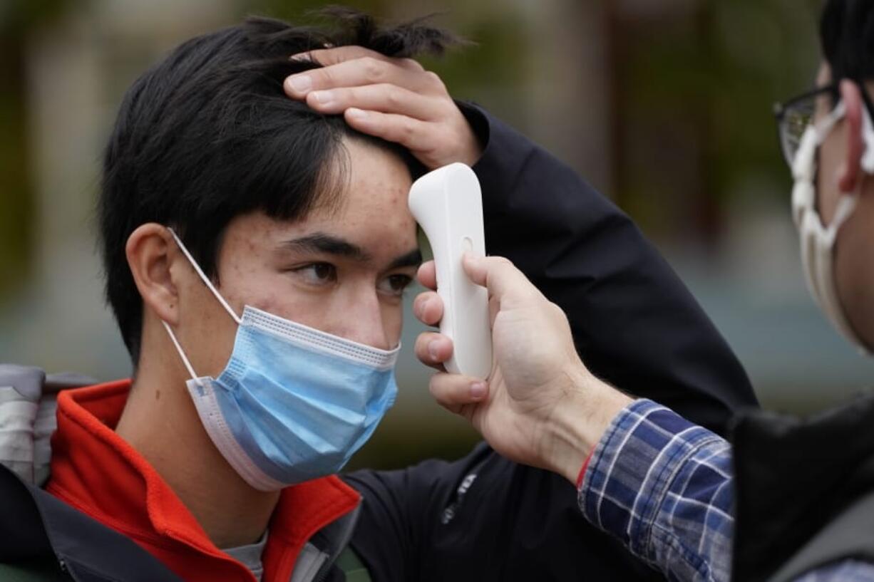 Will Surks of Westfield, N.J., a freshman at Bowdoin College, has his temperature checked Thursday as a safety measure before being allowed into a campaign event for Sara Gideon, Democratic candidate for U.S. Senate in Brunswick, Maine. (robert f.