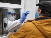 Medical staff takes a COVID-19 test at a coronavirus test center in Cologne, Germany, Thursday, Oct. 15, 2020. The city exceeded the important warning level of 50 new infections per 100,000 inhabitants in seven days. More and more German cities become official high risk corona hotspots with travel restrictions within Germany.