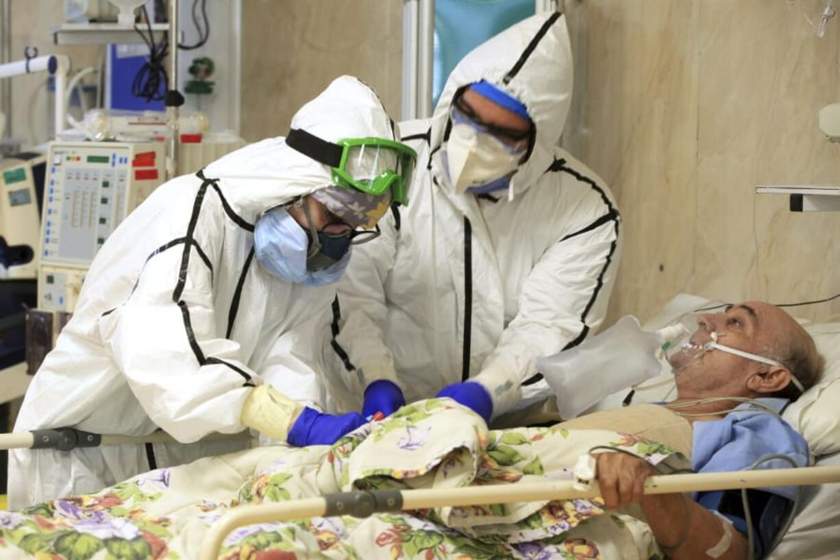 In this Wednesday, Oct. 14, 2020, photo provided by the Iranian Health Ministry, medics tend to a COVID-19 patient at the Shohadaye Tajrish Hospital in Tehran, Iran. Iran is confronting a new surge of infections that is filling hospitals and cemeteries alike.