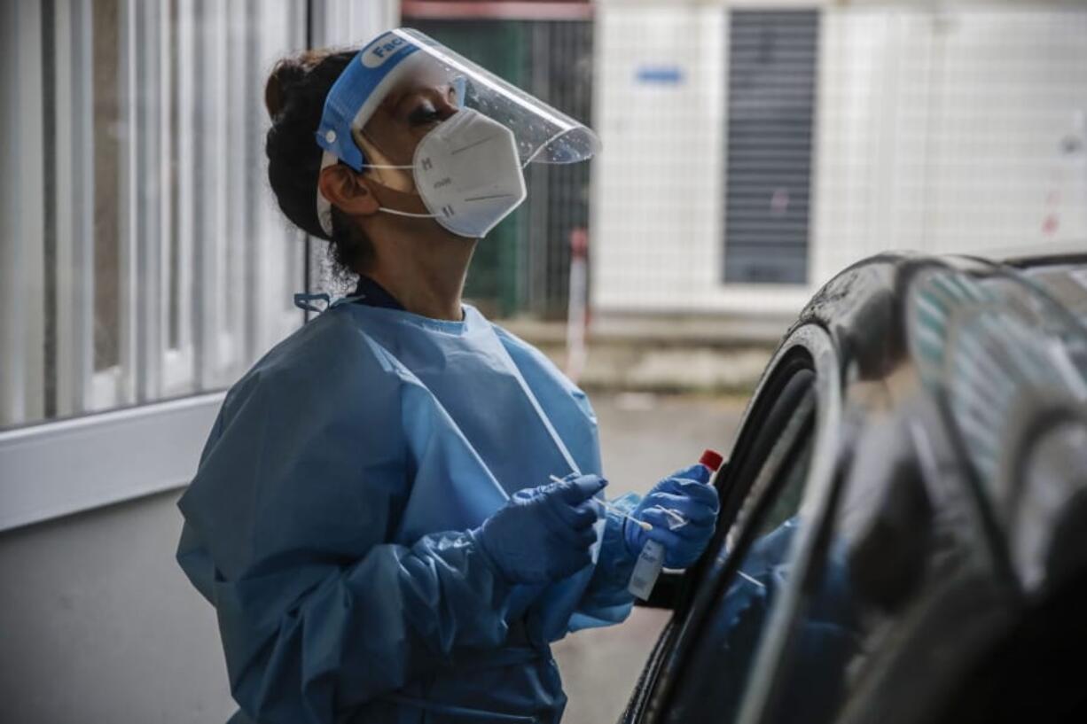 A paramedic takes swabs to test for COVID-19 at a drive-through at the San Paolo hospital, in Milan, Italy, Thursday, Oct. 15, 2020. Coronavirus infections are surging again in the region of northern Italy where the pandemic first took hold in Europe, renewing pressure on hospitals and health care workers.