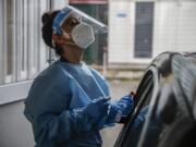 A paramedic takes swabs to test for COVID-19 at a drive-through at the San Paolo hospital, in Milan, Italy, Thursday, Oct. 15, 2020. Coronavirus infections are surging again in the region of northern Italy where the pandemic first took hold in Europe, renewing pressure on hospitals and health care workers.