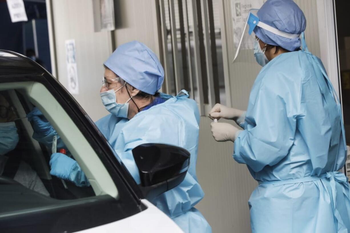 A medical staffer takes swabs as she tests for COVID-19 at a drive-through at the San Paolo hospital, in Milan, Italy, Wednesday, Oct. 14, 2020. Coronavirus infections are surging again in the Italian northern region where the pandemic first took hold in Europe, putting pressure again on hospitals and health care workers.