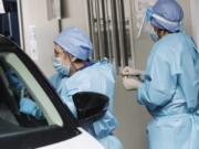 A medical staffer takes swabs as she tests for COVID-19 at a drive-through at the San Paolo hospital, in Milan, Italy, Wednesday, Oct. 14, 2020. Coronavirus infections are surging again in the Italian northern region where the pandemic first took hold in Europe, putting pressure again on hospitals and health care workers.