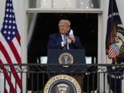 President Donald Trump removes his face mask to speak from the Blue Room Balcony of the White House to a crowd of supporters, Saturday, Oct. 10, 2020, in Washington.