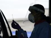 FILE - In this Oct. 23, 2020, file photo, University of Washington research coordinator Rhoshni Prabhu holds up a swab after testing a passenger at a free COVID testing site in Seattle. Deaths per day from the coronavirus in the U.S. are on the rise again, just as health experts had feared, and cases are climbing in nearly every single state.