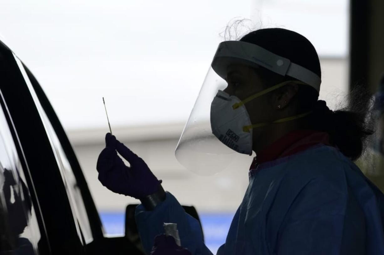 FILE - In this Oct. 23, 2020, file photo, University of Washington research coordinator Rhoshni Prabhu holds up a swab after testing a passenger at a free COVID testing site in Seattle. Deaths per day from the coronavirus in the U.S. are on the rise again, just as health experts had feared, and cases are climbing in nearly every single state.