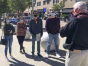 In this Sept. 20, 2020, photo, tour guide John Erardi, right, talks with a tour group on the sidewalk outside the Cincinnati Reds Great American Ball Park in Cincinnati. The walking tour was one of the few groups of people on the street as the Reds and White Sox were inside just an hour before the game without fans because of the pandemic.