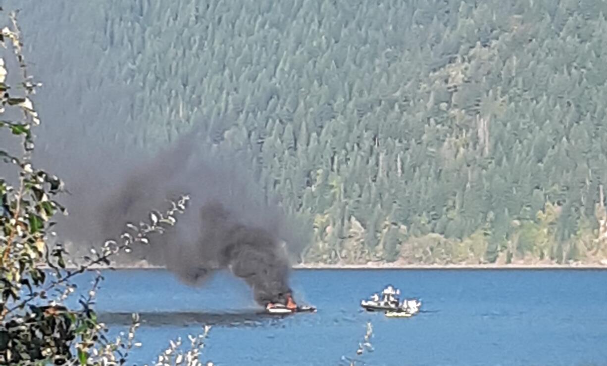 The remains of a boat smolders at a dock in Yale Lake on Saturday. Two people were burned in the fire.