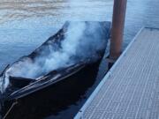 The remains of a boat smolders at a dock in Yale Lake on Saturday. Two people were injured in the fire.