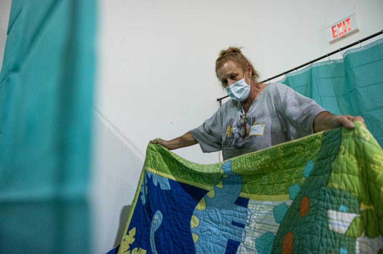 Diana Finn spreads a quilt over her sleeping mat at the Winter Hospitality Overflow shelter at St. Andrew Lutheran Church in Orchards on Monday.