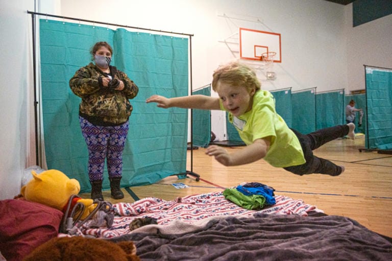 Aaron Morris, 6, leaps onto his mattress while his mother, Merissa Morris, looks on before a night at the Winter Hospitality Overflow shelter at St. Andrew Lutheran Church in Orchards on Monday.