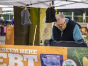 Volunteer Tim Aufmuth processes an Electronic Benefits Transfer card Saturday at the Vancouver Farmers Market's information booth. Customers can redeem their food benefits at the information booth and get a $20 match for fresh fruits and vegetables purchased at the market through the SNAP Market Match program.