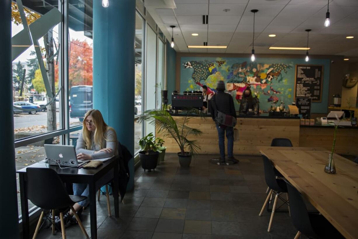 Customer Emily Carroll of Vancouver works on her laptop while stopping by Kafiex Roasters Coffee Lab in downtown Vancouver on Monday afternoon.