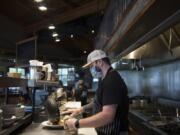 Chef Caleb Johnson plates up a shrimp teriyaki rice bowl for a customer while working at Beaches restaurant Monday morning. Restaurants are required to switch to take-out or outdoor-only seating starting Tuesday.