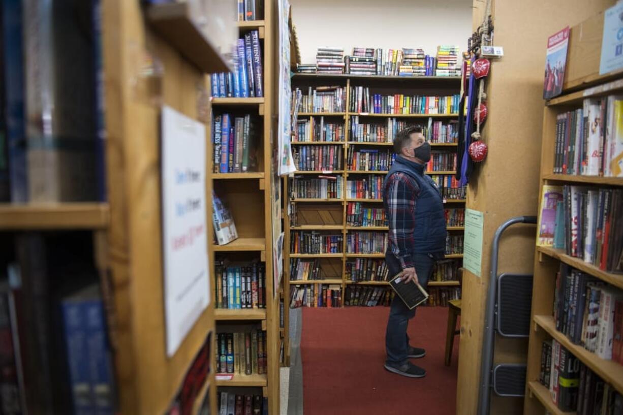 Vancouver resident Tracy Sand wears a protective face mask while browsing through the wide selection at Vintage Books. The store allows a maximum of 10 people in the store at any time.