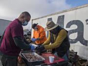 Daddy D&#039;s Southern Style BBQ owner Donnie Vercher, left, joins volunteers Chase Alderman and Michael Campbell as they prepare smoked turkey on Friday afternoon. The trio helped make free Thanksgiving meals to feed 3,000 people in 2020.