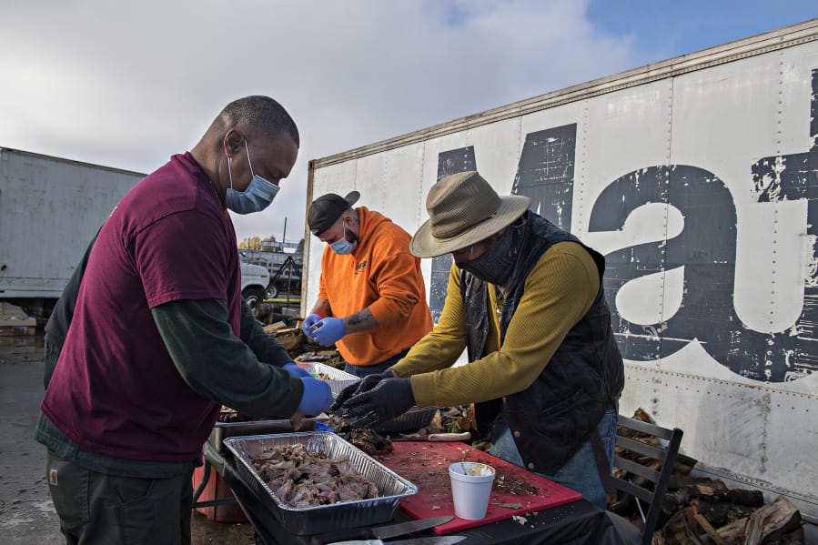 Daddy D&#039;s Southern Style BBQ owner Donnie Vercher, left, joins volunteers Chase Alderman and Michael Campbell as they prepare smoked turkey on Friday afternoon. The trio helped make free Thanksgiving meals to feed 3,000 people in 2020.