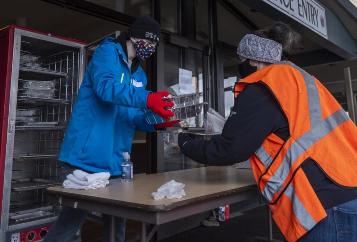 Taylor Scheetz, 14, left, hands packaged Thanksgiving meals to Sara Scheetz, both of Vancouver, during a Thanksgiving meal distribution event at WareHouse &#039;23 in Vancouver. Owner Mark Matthias said the restaurant anticipated serving as many as 1,500 meals over the course of the day.