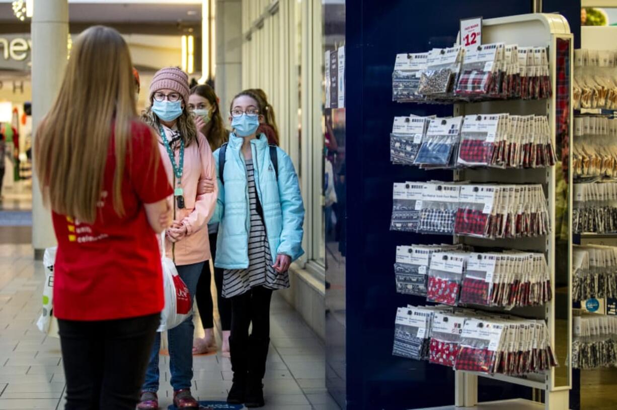 Jennifer Lindsay and her daughter Elsa, 11, talk with an Old Navy employee as they wait in a socially distanced line on Friday at Vancouver Mall. Black Friday shoppers were a bit less numerous than usual in the morning, but foot traffic picked up in the afternoon.