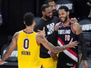 Los Angeles Lakers' Kyle Kuzma (0) and LeBron James, center, greet Portland Trail Blazers' Carmelo Anthony (00) after an NBA basketball first round playoff game Saturday, Aug. 29, 2020, in Lake Buena Vista, Fla. The Lakers won 131-122 to win the series 4-1.