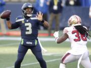 Seattle Seahawks quarterback Russell Wilson (3) makes a touchdown pass to wide receiver DK Metcalf (not shown) as San Francisco 49ers safety Marcell Harris, right, pressures during the first half of an NFL football game, Sunday, Nov. 1, 2020, in Seattle.