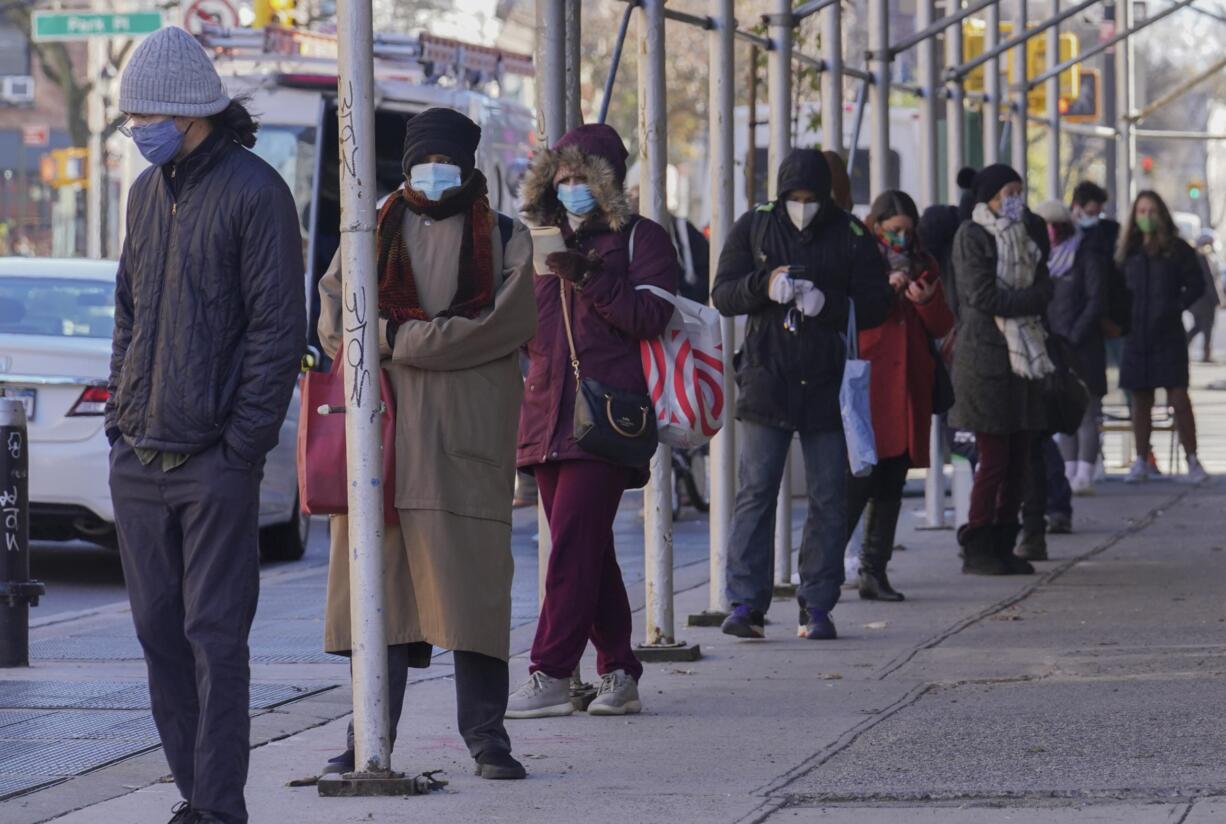 FILE - People wait on a line stretching around a block for a clinic offering COVID-19 testing, Wednesday, Nov. 18, 2020, in the Park Slope area of the Brooklyn borough of New York. The lines for free COVID-19 tests stretch for blocks and hours in cities feeling the dual strain of the coronavirus surge and holiday plans. But $150 or more can buy a spot at the front of the queue. Some are turning to of one of an increasing number of pop-up clinics that promise visitors instant results — at a cost.