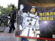 In this photo taken Thursday, Oct 23, 2003, a man pushes his bicycle past the cover of a magazine showing China&#039;s first man in space, Yang Liwei and the Chinese characters for &quot;How far are we from the moon?&quot; at a newsstand in Beijing, China. China&#039;s Nov. 24, 2020, trip to the moon and, presumably, back is the latest milestone in the Asian powerhouse&#039;s slow but steady ascent to the stars.