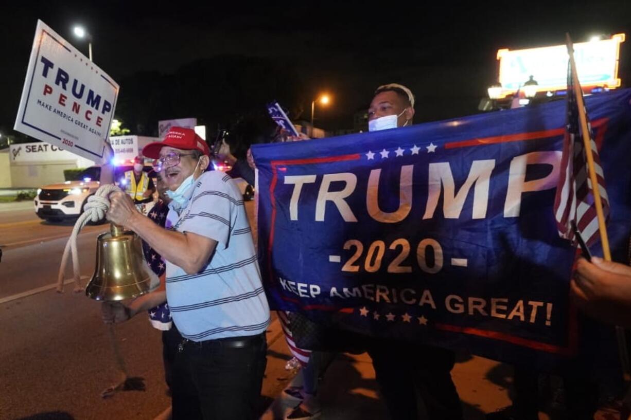 In this Nov. 3, 2020, photo, Rafael Fagundo rings a bell as he and other supporters of President Donald Trump chant and wave flags outside the Versailles Cuban restaurant during a celebration on election night in the Little Havana neighborhood of Miami. As election postmortems go, the one that began in Florida Wednesday was especially wrenching for Democrats. While they could share in the possibility of a Biden victory, as other battleground states continue to tally votes, the soul searching and second-guessing has begun amid another high-profile loss at the ballot box.