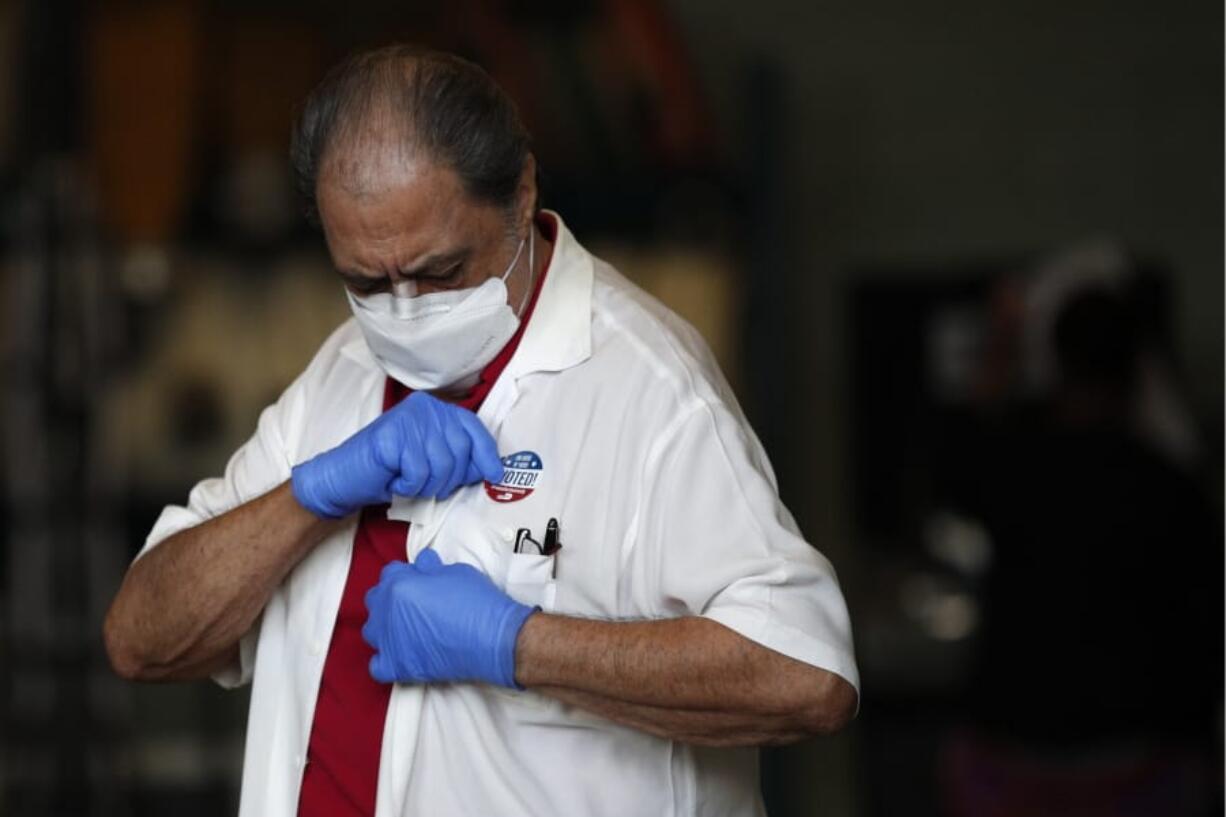 A man wearing gloves and a mask to protect against COVID-19 affixes an &quot;I voted&quot; sticker to his shirt as he leaves a polling place at Indian Creek Fire Station #4 in Miami Beach, Fla., on Election Day, Tuesday, Nov. 3, 2020.(AP Photo/Rebecca Blackwell) (Robert Cohen/St.