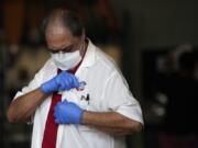 A man wearing gloves and a mask to protect against COVID-19 affixes an &quot;I voted&quot; sticker to his shirt as he leaves a polling place at Indian Creek Fire Station #4 in Miami Beach, Fla., on Election Day, Tuesday, Nov. 3, 2020.(AP Photo/Rebecca Blackwell) (Robert Cohen/St.