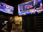 Bartender Sam Schilke watches election results on television at a bar and grill Tuesday, Nov. 3, 2020, in Portland, Ore.