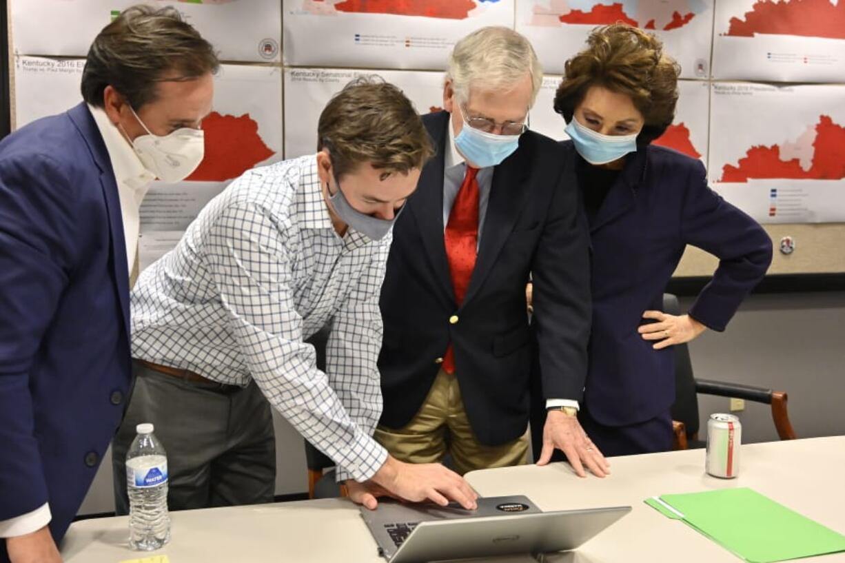 Republican Senate candidate Sen. Mitch McConnell, second from right, and his wife, Elaine Chao, right, look on as aides show him the election results in Louisville, Ky., Tuesday, Nov. 3, 2020. (AP Photo/Timothy D.