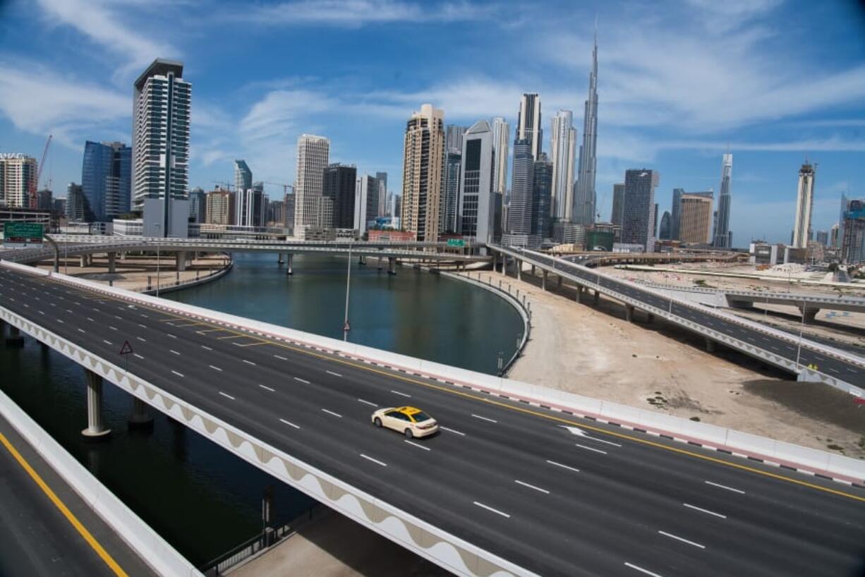 A lone taxi cab travels along a highway in front of the Dubai skyline in April.