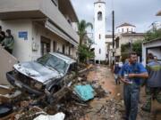 Local residents try to clean a road of debris after torrential rainfall in the village of Malia on the island of Crete, southern Greece, Tuesday, Nov. 10, 2020. Heavy flooding on the Greek island of Crete damaged roads, flooded hundreds of homes, and swept cars into the sea amid ongoing torrential rainfall.