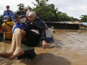 A National Police officer carries an elderly woman out of an area flooded by water brought by Hurricane Eta in Jerusalen, Honduras, Thursday, Nov. 5, 2020. The storm that hit Nicaragua as a Category 4 hurricane on Tuesday had become more of a vast tropical rainstorm, but it was advancing so slowly and dumping so much rain that much of Central America remained on high alert.