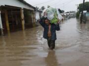 A man walks in knee-deep floodwaters carrying belongings in San Manuel, Honduras, Wednesday, Nov. 4, 2020. Eta weakened from the Category 4 hurricane to a tropical storm after lashing the Caribbean coast for much of Tuesday, its floodwaters isolating already remote communities and setting off deadly landslides.