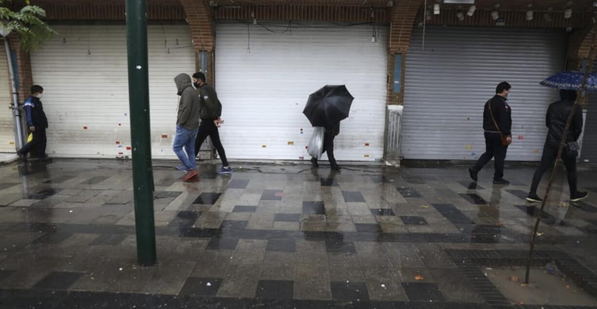 People walk in front of closed shops at Tehran&#039;s Grand Bazaar, Iran&#039;s main business and trade hub, Satuday, Nov. 21, 2020. Iran on Saturday shuttered businesses and curtailed travel between its major cities, including the capital of Tehran, as it grapples with the worst outbreak of the coronavirus in the Mideast region.