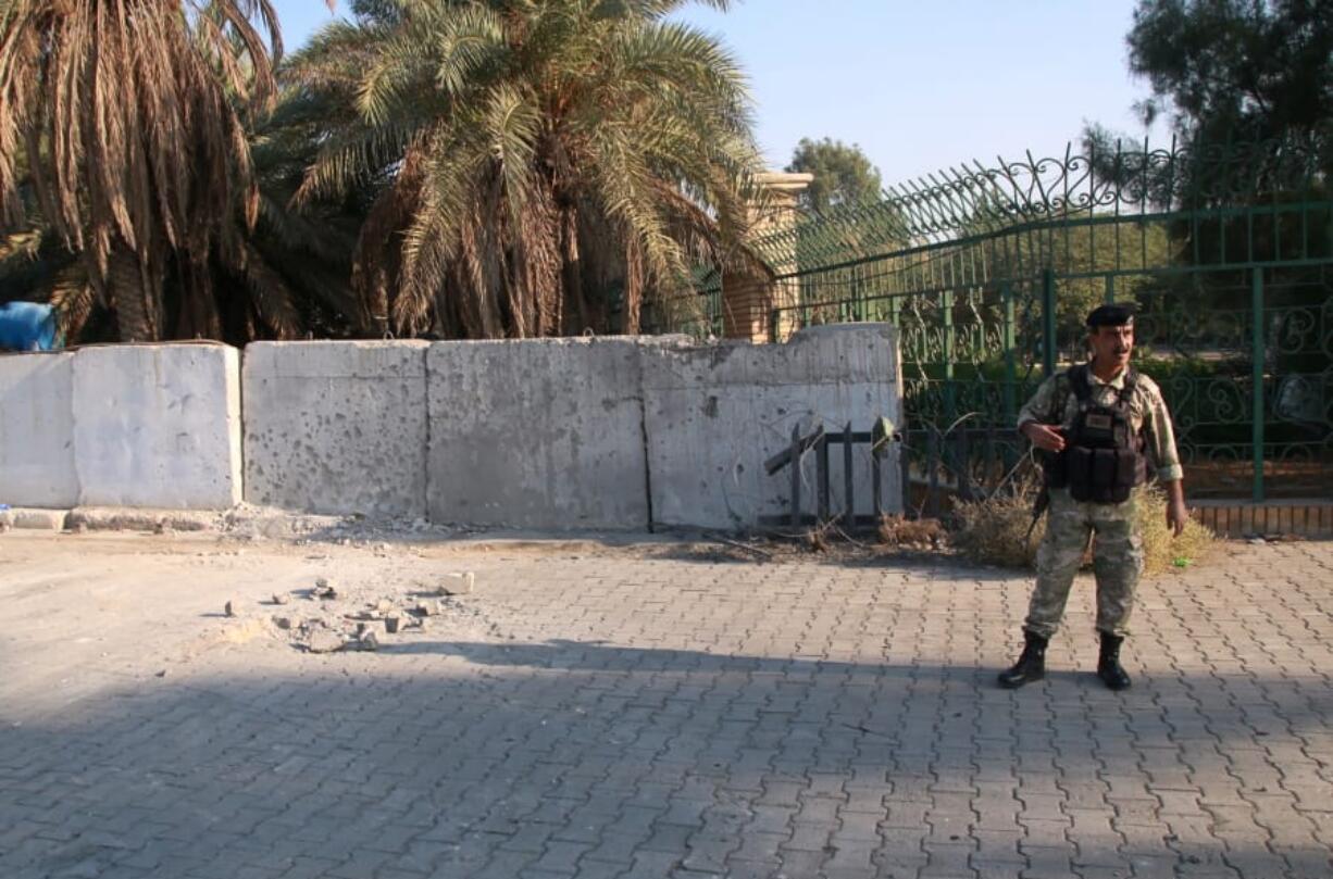 An army soldier inspects the scene of the rocket attack at the gate of al-Zawra public park in Baghdad, Iraq, Wednesday, Nov. 18, 2020.