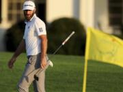 Dustin Johnson looks over his shot on the 18th green next to the Masters yellow flag during the third round of the Masters golf tournament Saturday, Nov. 14, 2020, in Augusta, Ga.