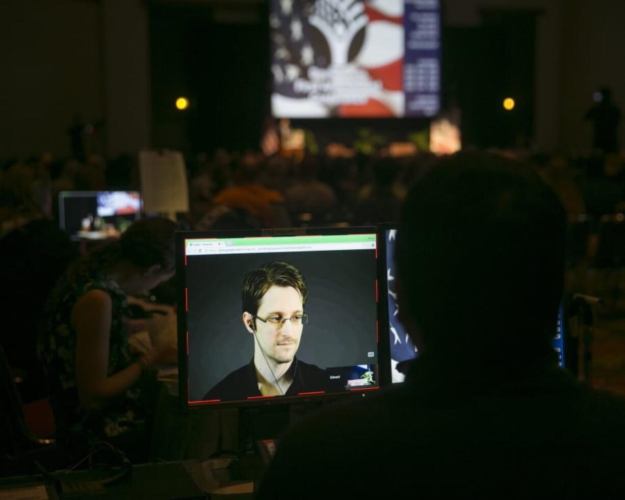 FILE  - In this Saturday, Feb. 14, 2015 file photo, a video technician monitors a computer screen as National Security Agency leaker Edward Snowden appears on a live video feed broadcast from Moscow at an event sponsored by the ACLU Hawaii in Honolulu. Former U.S. security contractor Edward Snowden says he will apply for Russian citizenship but not renounce his U.S. citizenship. The former contractor for the National Security Agency has been living in Russia since 2013 to escape prosecution in the U.S. after leaking classified documents detailing government surveillance programs.