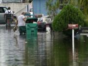 Residents clear debris from a flooded street in the Driftwood Acres Mobile Home Park, in the aftermath of Tropical Storm Eta, Tuesday, Nov. 10, 2020, in Davie, Fla. Tropical Storm Eta was squatting off western Cuba on Tuesday after drifting away from South Florida, where it unleashed a deluge that flooded entire neighborhoods and covered the floors of some homes and businesses.