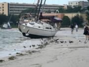 People walk past boats on the beach in the aftermath of Tropical Storm Eta, Thursday, Nov. 12, 2020, in Gulfport, Fla. Eta dumped torrents of blustery rain on Florida&#039;s west coast as it slogged over the state before making landfall near Cedar Key, Fla.